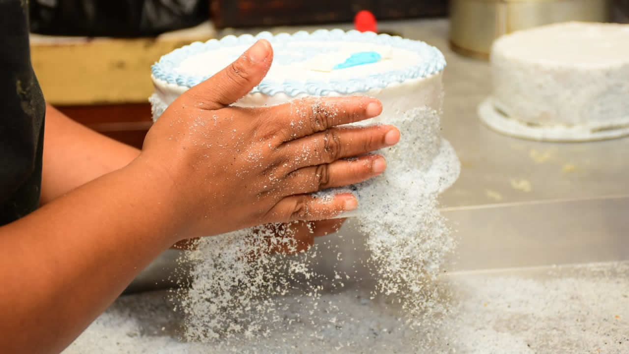 Et la dernière touche : le pâtissier pare le gâteau de coco en poudre qui sert  de paillettes.