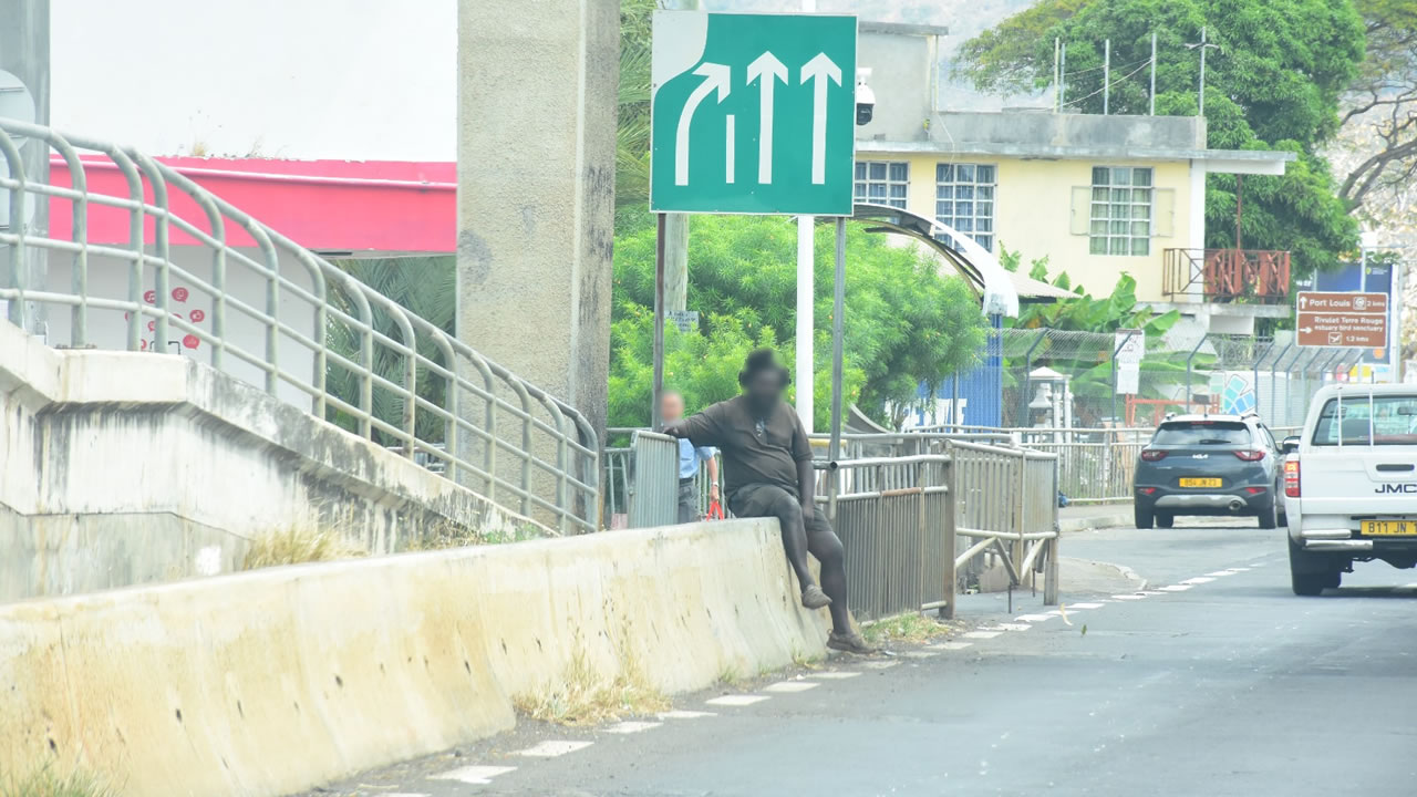 Une personne s'assied en bordure de route sans se soucier de la circulation.